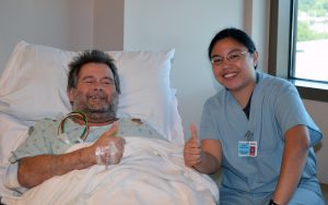 Nurse sitting next to man in hospital bed