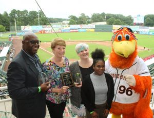 People accepting awards with mascot baseball field