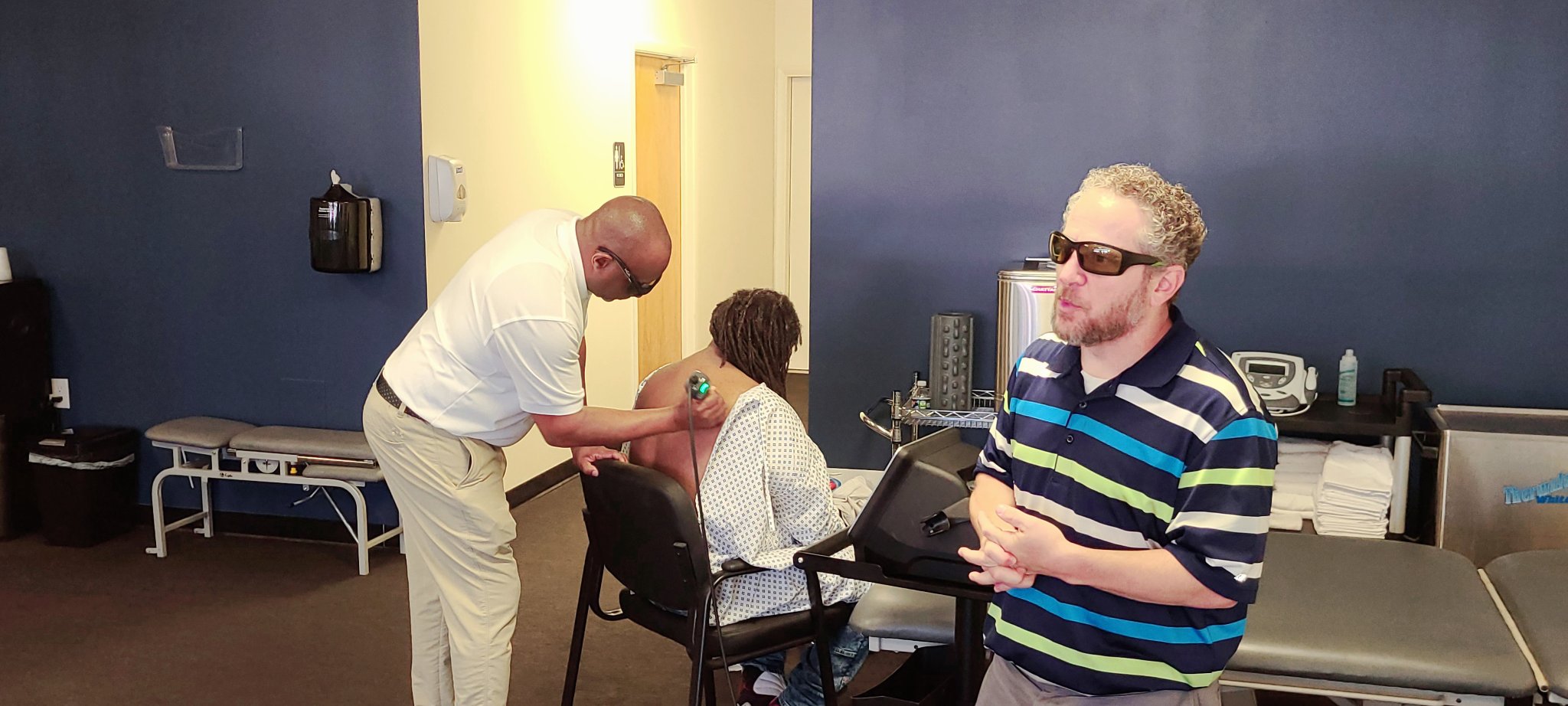 Adam Marmon, a representative from Enovis-LightForce Lasers explained treatment, while Dr. Briddell performed deep tissue laser therapy on a patient