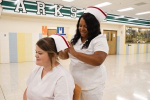 LPN CAP PINNING: Nicole Norman of Salisbury helps pin a cap on Amy Cannon of Berlin at the Wor-Wic Community College nursing awards and recognition ceremony.