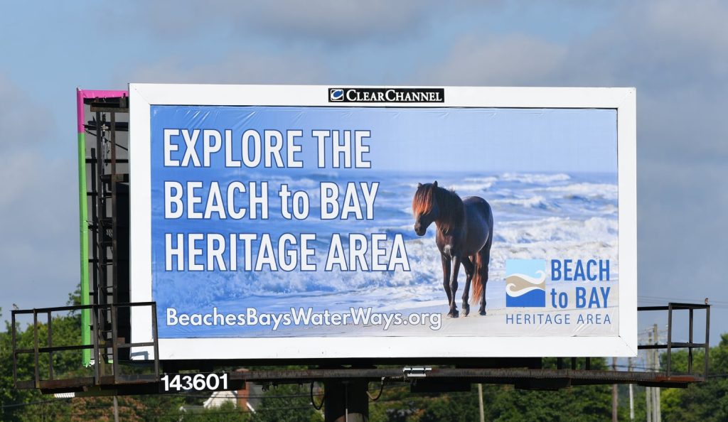 billboard explore the beach to bay heritage area with horse on beach