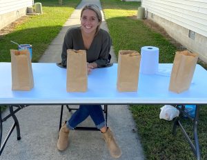 Girl sitting at a table outdoors with paper bags on the table
