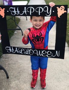Kid dressed up as Spiderman holding a picture frame