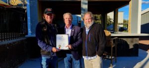 Three men holding a proclamation