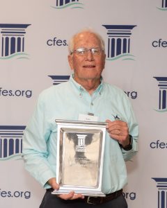 Older gentleman in a mint green shirt holding an award