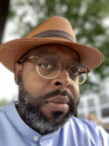 Close up image of a man in a hat with glasses