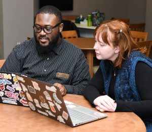 Two students studying with laptops on a table