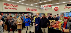 Group of people in coats and jackets in the produce section of a grocery store