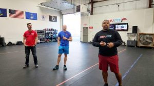 Three men in a gym explaining training programs