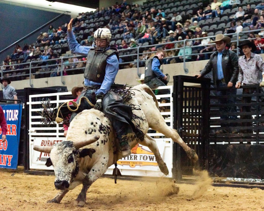 guy riding bull at rodeo event