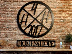 Round metal sign that reads Homes for Hope