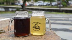 two glass mugs full of beer on table