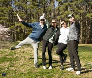 four people standing on golf course