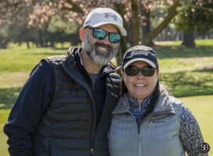 man and woman standing on golf course smiling