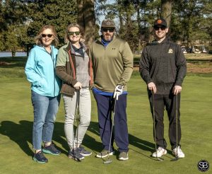 group of 4 golfers standing on golf course