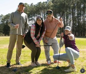 group of 4 people posing on golf course