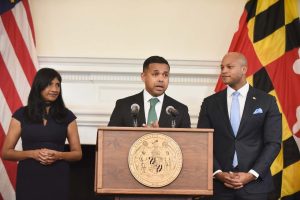 three government officials speaking at podium with maryland and us flags