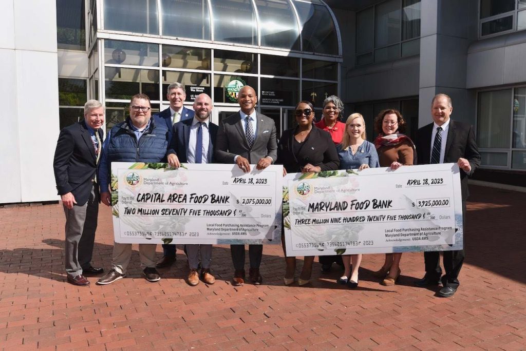 governor wes moore with group holding large food bank checks