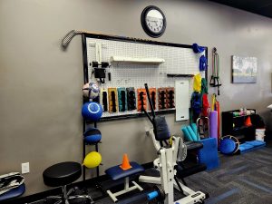 physical therapy items on wall with machine and clock