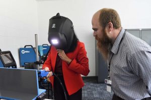 female welding with man watching