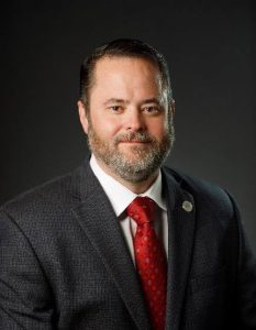 headshot of man wearing suit and tie