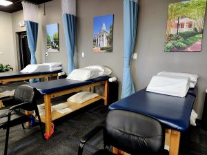 three physical therapy tables with pictures on wall
