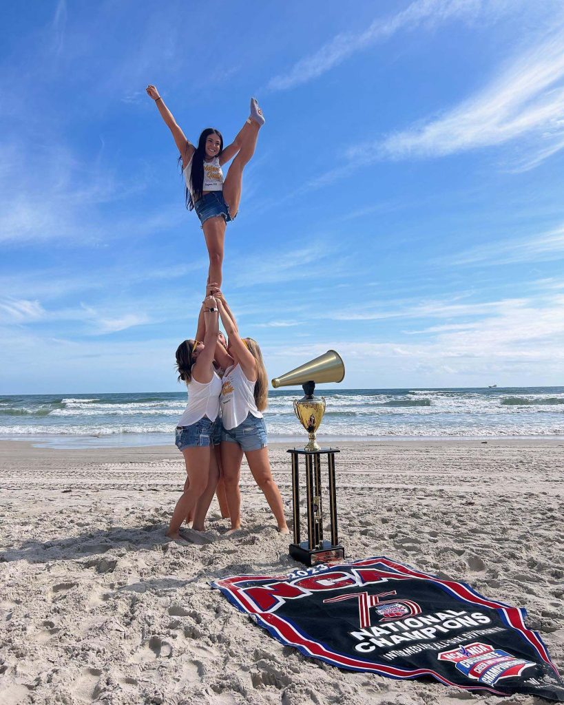 cheerleaders practicing on beach with trophy