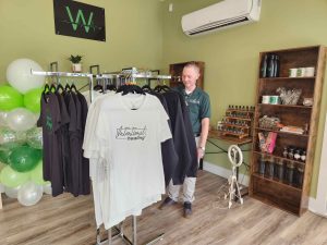 man standing in store with shirts and wellness products