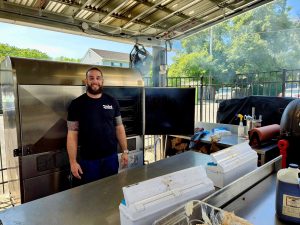 owner of Taylor's BBQ standing in front of barbecue cooker