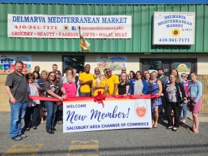Group of people standing outside the Mediterranean Market cutting a large ribbon