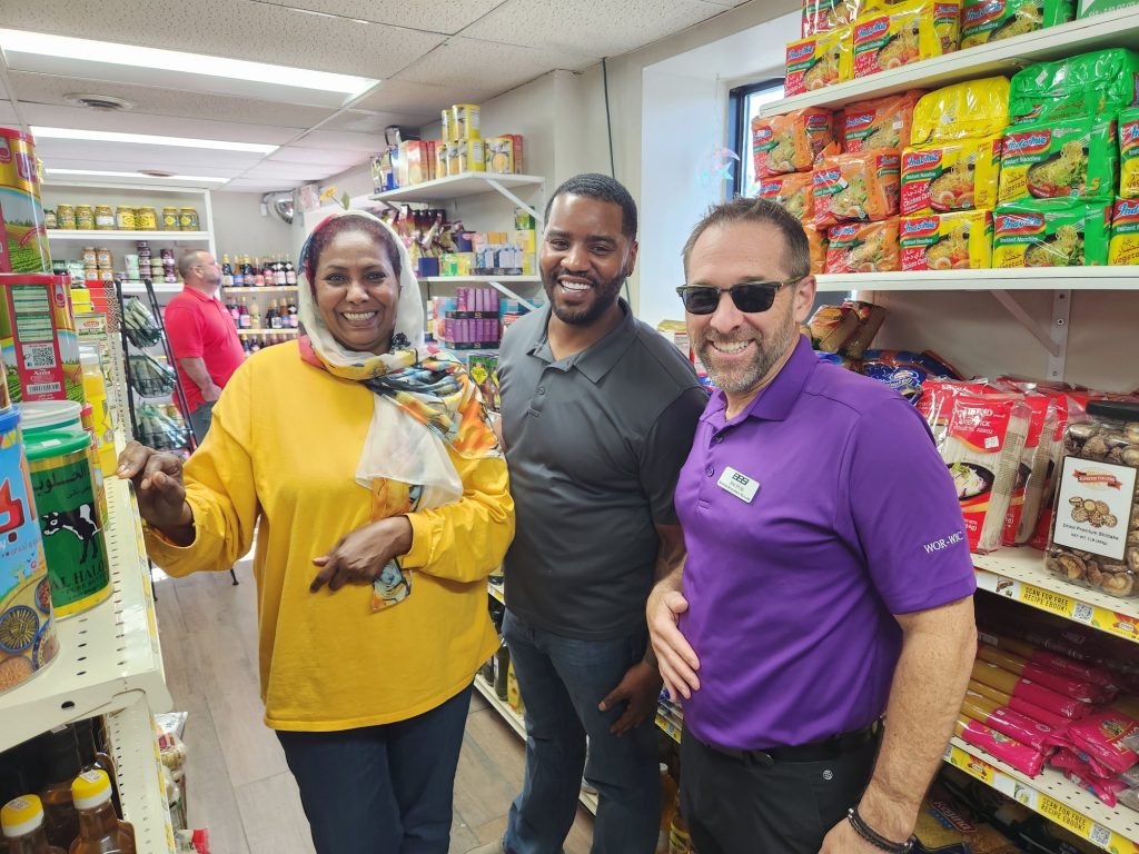 Beautiful woman with head scarf smiling beside a man in a black shirt and man in a purple shirt