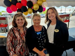 Three women standing under a large tent with balloons