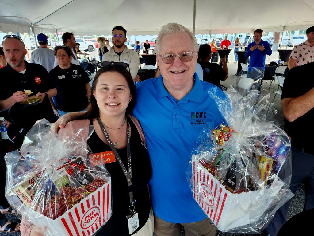 Man in a blue shirt and woman in a black shirt, both holding popcorn gift baskets