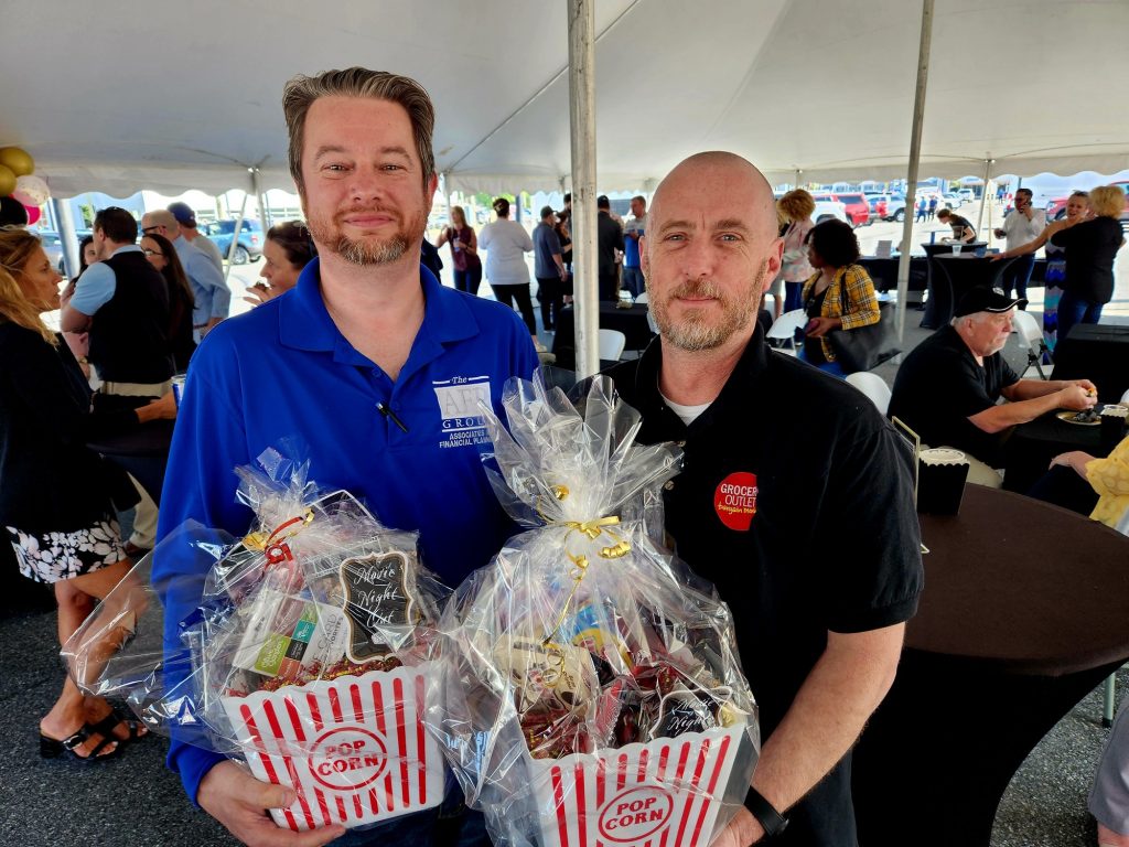 Two men, both holding popcorn gift baskets