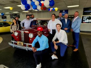 Group of people standing around a red jeep