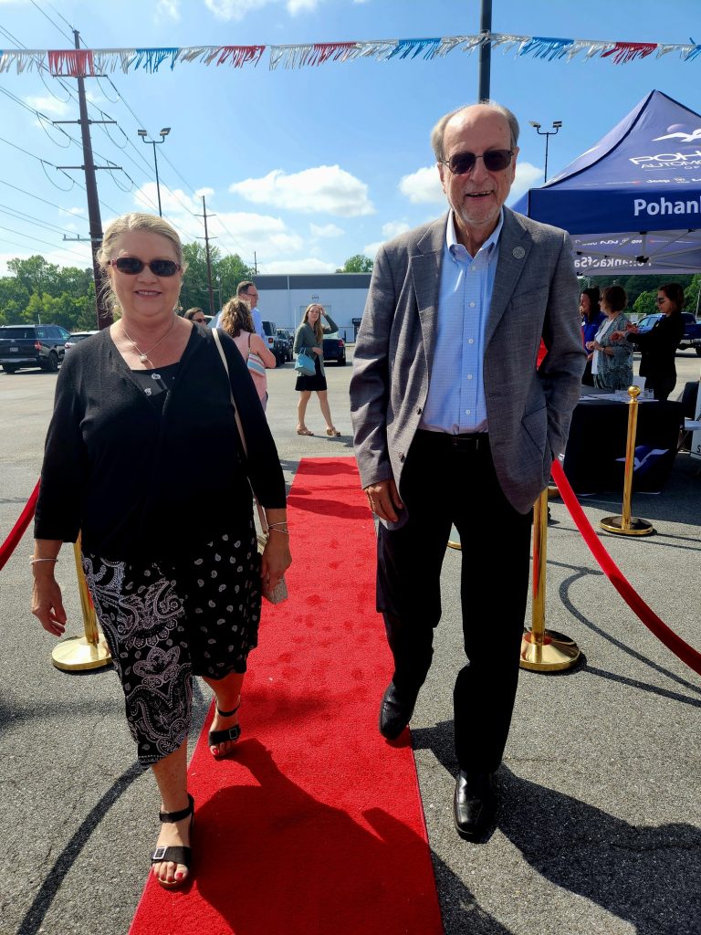 Man in a suite and woman in a back shirt walking down a red carpet