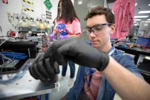 nasa student wearing gloves and goggles doing research