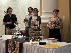four people standing at the ugly pie table full of desserts