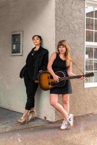 two ladies standing together with guitar