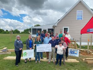 group of people standing outside house holding check by United Way