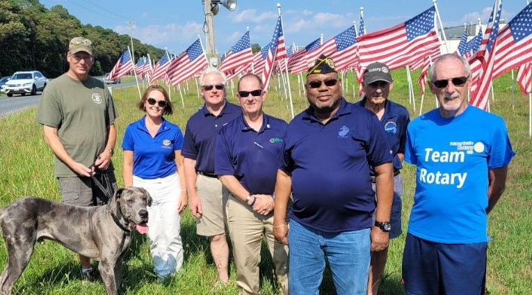 Group of veterans and Rotarians standing with American flags