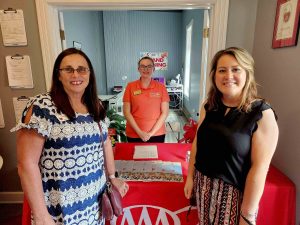 three ladies standing at AAA table for event