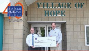 two guys holding check outside Village of Hope building