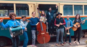 band members playing instruments standing outside trolley bus