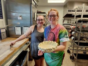 two girls in kitchen holding pie