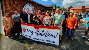 group of people holding congratulations banner outside