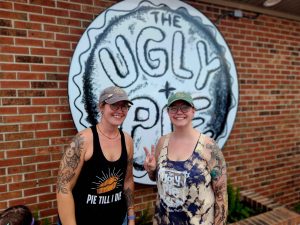 two girls standing in front of the ugly pie sign