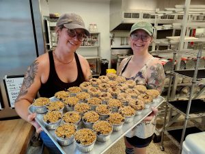 two girls holding tray of pies in kitchen
