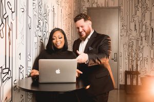 Two people looking at a MacBook computer and smiling