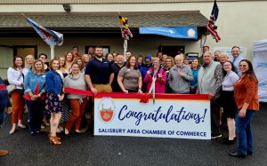 Large group of people standing behind a banner for a ribbon cutting ceremony